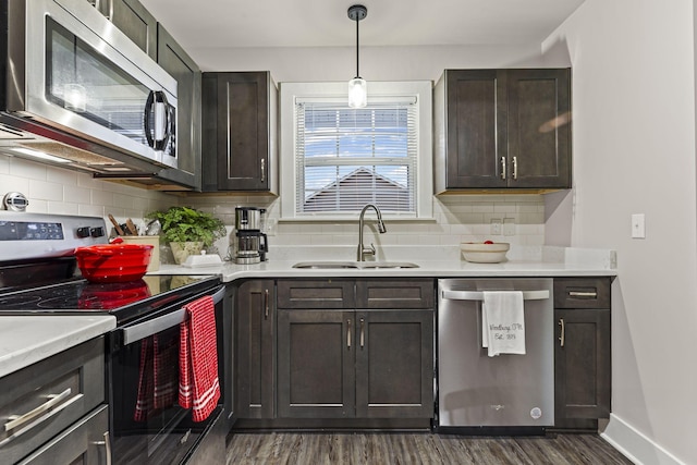 kitchen featuring sink, hanging light fixtures, dark brown cabinets, dark hardwood / wood-style floors, and stainless steel appliances