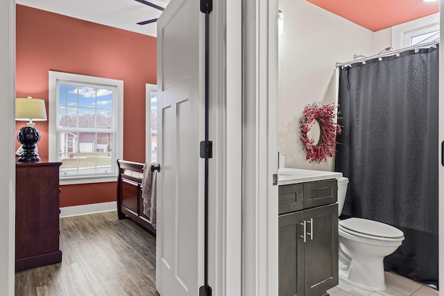 bathroom with hardwood / wood-style flooring, ceiling fan, a shower with shower curtain, vanity, and toilet