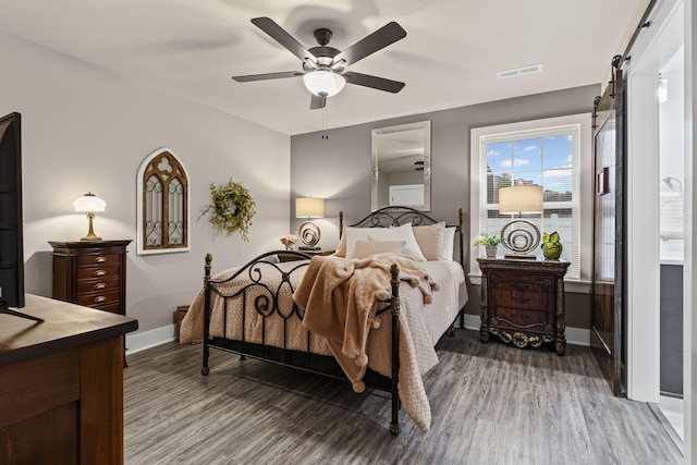 bedroom with wood-type flooring, a barn door, and ceiling fan