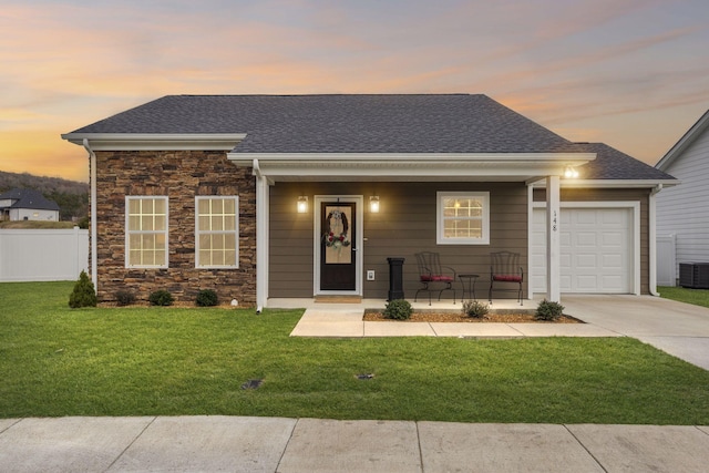 view of front of home with a porch, a garage, and a lawn