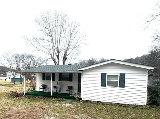 rear view of house featuring a yard and covered porch