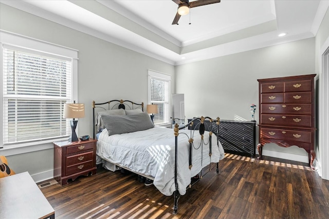 bedroom with a raised ceiling, ornamental molding, dark wood-type flooring, and ceiling fan