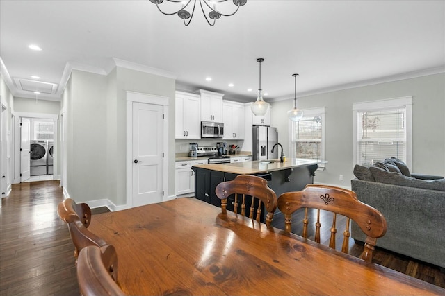 dining room featuring separate washer and dryer, sink, crown molding, and dark wood-type flooring