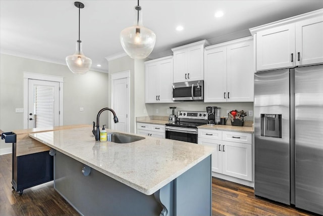 kitchen featuring decorative light fixtures, stainless steel appliances, an island with sink, and white cabinets