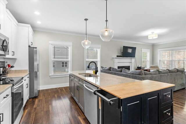 kitchen with sink, appliances with stainless steel finishes, dark hardwood / wood-style floors, an island with sink, and white cabinets