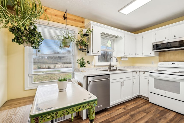 kitchen with appliances with stainless steel finishes, sink, white cabinets, and dark hardwood / wood-style flooring