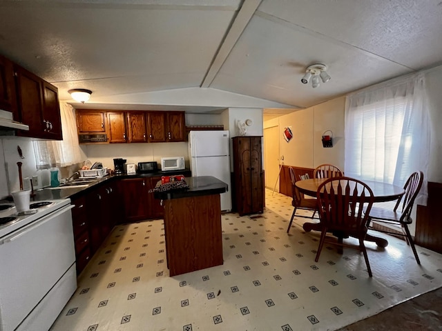 kitchen with white appliances, lofted ceiling, sink, and a kitchen island