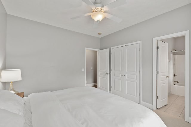 tiled bedroom featuring ceiling fan, ensuite bathroom, and a closet