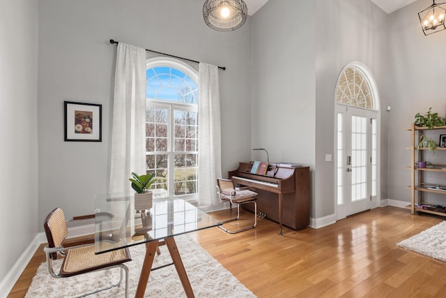 living area with a towering ceiling, light hardwood / wood-style flooring, and a notable chandelier