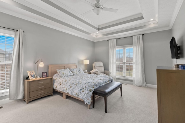 bedroom featuring crown molding, ceiling fan, a tray ceiling, and light carpet