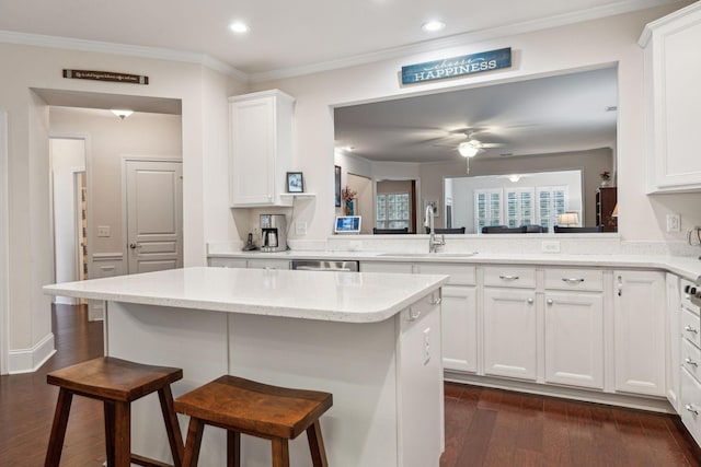 kitchen with sink, white cabinets, dark hardwood / wood-style flooring, a kitchen bar, and kitchen peninsula