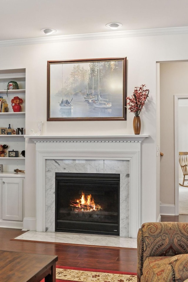 interior details with hardwood / wood-style flooring, ornamental molding, a fireplace, and built in shelves