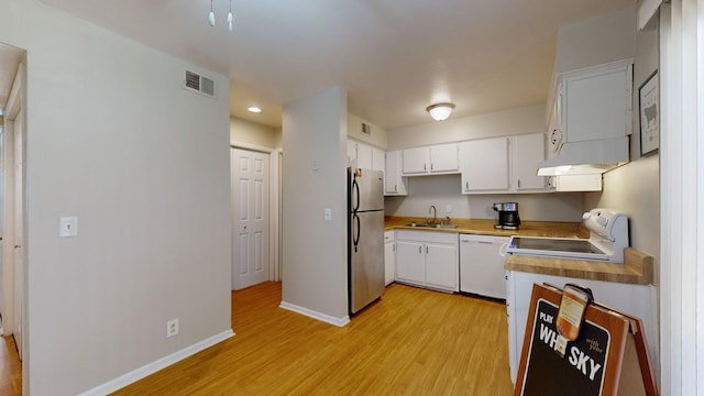 kitchen featuring white appliances, visible vents, light wood-type flooring, under cabinet range hood, and a sink