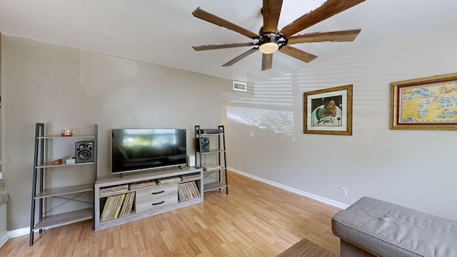 living area with visible vents, vaulted ceiling, ceiling fan, wood finished floors, and baseboards