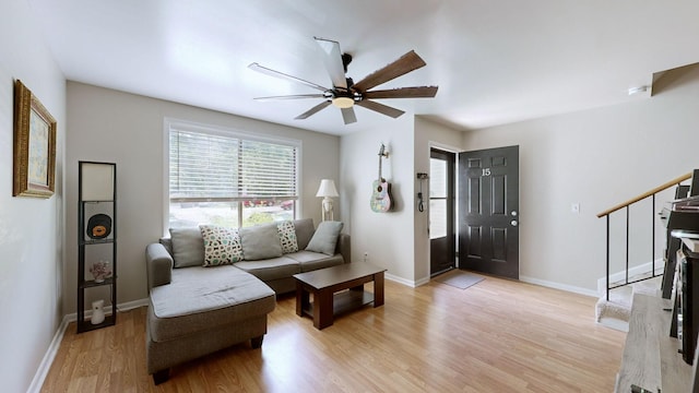 foyer entrance with light wood-style flooring, stairs, baseboards, and a ceiling fan