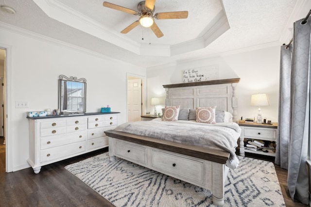 bedroom with ceiling fan, a tray ceiling, ornamental molding, a textured ceiling, and dark hardwood / wood-style flooring