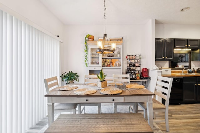 dining room featuring light hardwood / wood-style floors, sink, and a notable chandelier