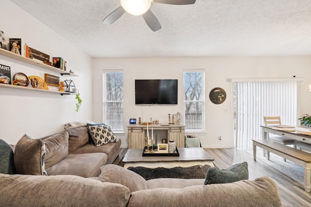 living room with ceiling fan, a healthy amount of sunlight, a textured ceiling, and light wood-type flooring