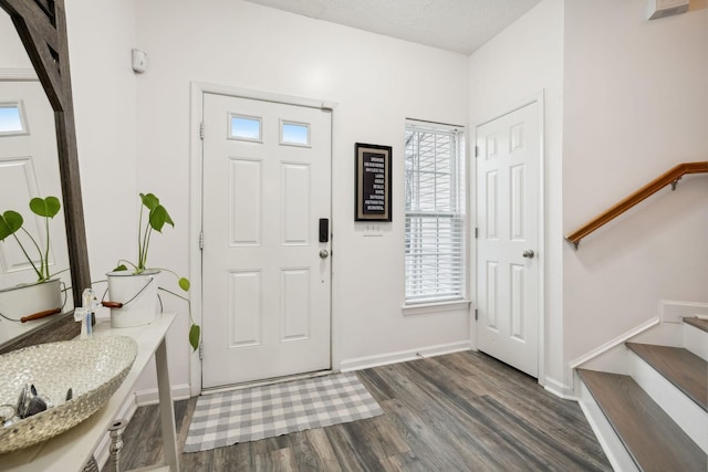 entrance foyer with dark wood-type flooring and a textured ceiling