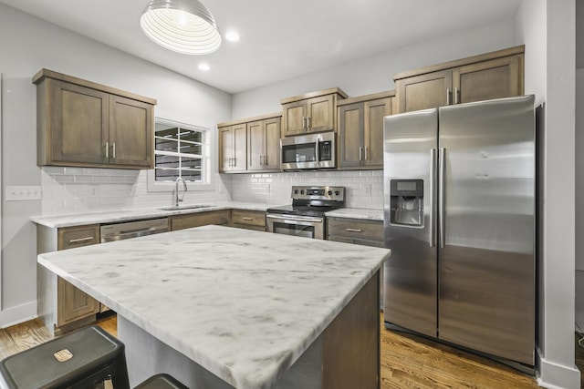 kitchen with appliances with stainless steel finishes, dark hardwood / wood-style floors, tasteful backsplash, sink, and a center island