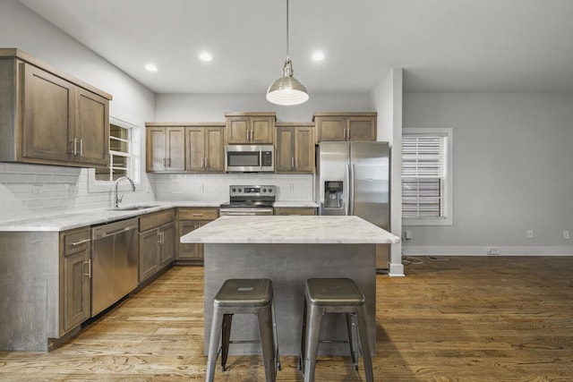 kitchen with pendant lighting, sink, a breakfast bar area, appliances with stainless steel finishes, and a kitchen island