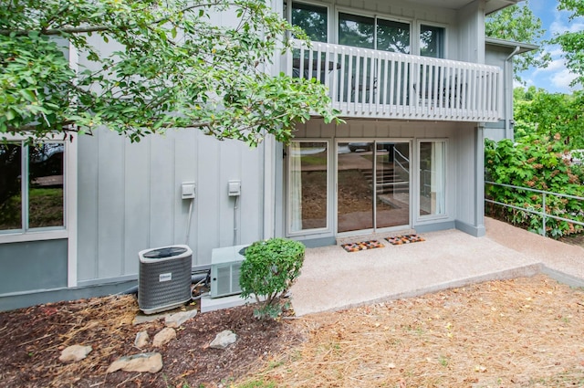 view of exterior entry with a balcony and central air condition unit