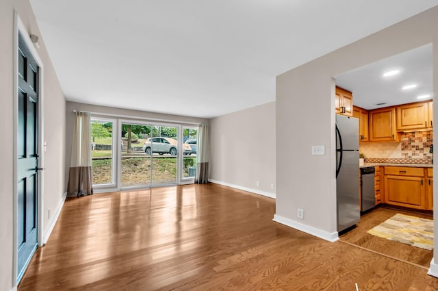 kitchen featuring decorative backsplash, stainless steel appliances, and light wood-type flooring