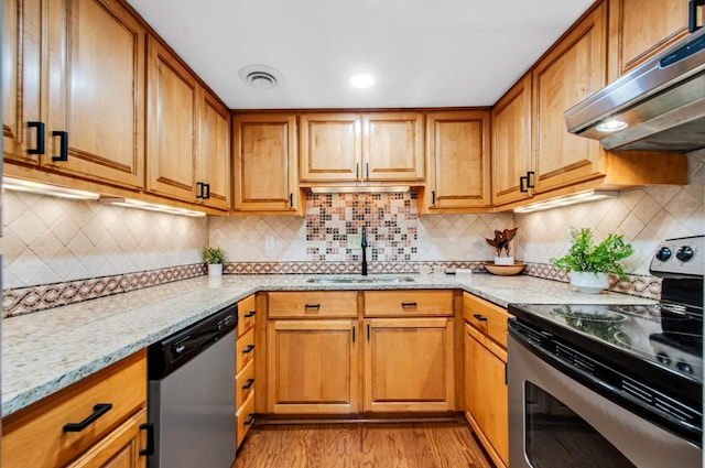 kitchen featuring sink, light stone counters, appliances with stainless steel finishes, light hardwood / wood-style floors, and backsplash