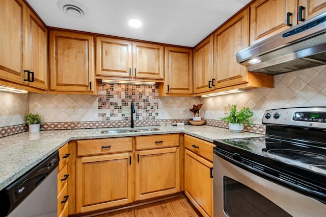 kitchen with sink, decorative backsplash, light stone counters, stainless steel appliances, and light wood-type flooring