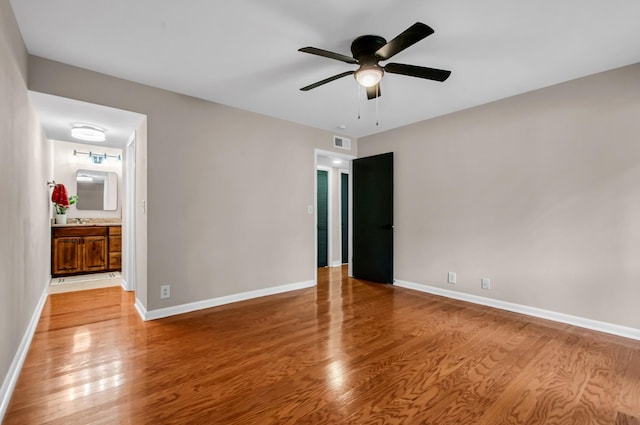 unfurnished bedroom featuring ensuite bathroom, ceiling fan, and light wood-type flooring