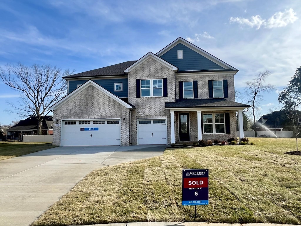 view of front of home featuring brick siding, driveway, a front lawn, and fence