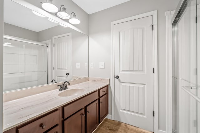 full bath with a shower stall, wood finished floors, and vanity