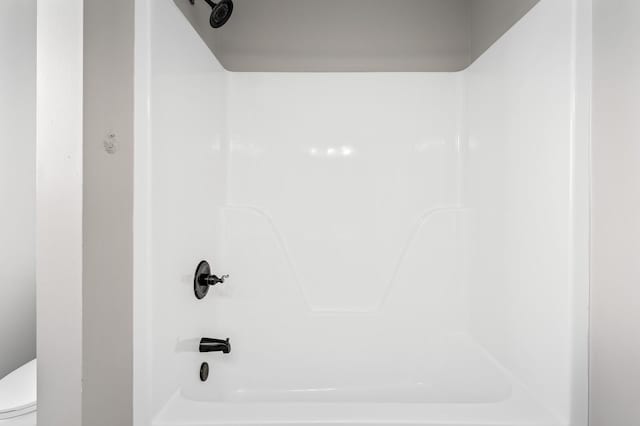 bathroom featuring shower / washtub combination and toilet