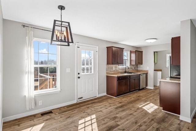 kitchen featuring hanging light fixtures, stainless steel dishwasher, light wood-style floors, dark brown cabinetry, and a sink