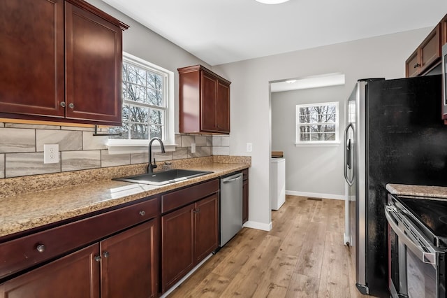 kitchen featuring light wood-type flooring, appliances with stainless steel finishes, backsplash, and a sink