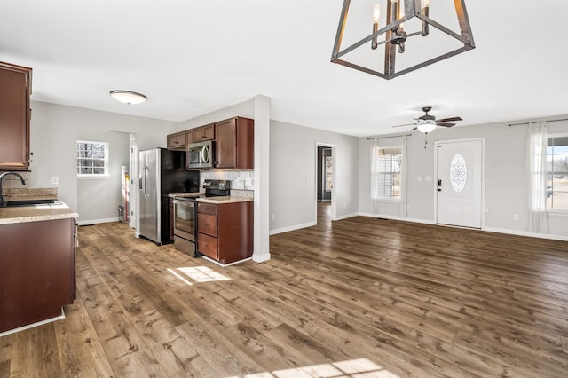 kitchen with plenty of natural light, appliances with stainless steel finishes, wood finished floors, light countertops, and a sink