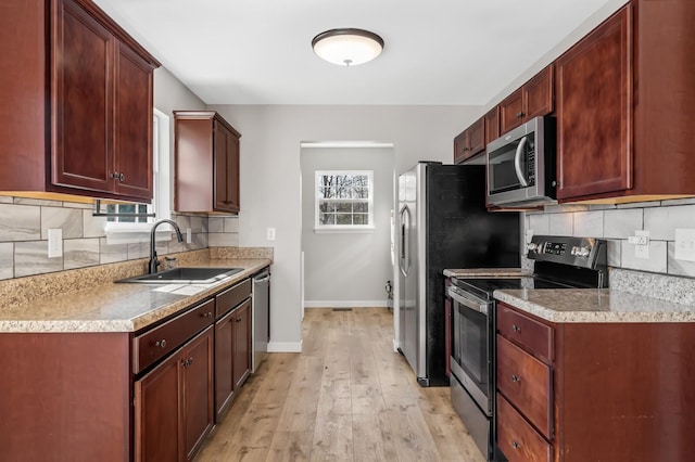 kitchen with stainless steel appliances, a sink, light countertops, and baseboards