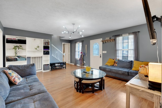 living room featuring an inviting chandelier, a textured ceiling, and light wood-type flooring