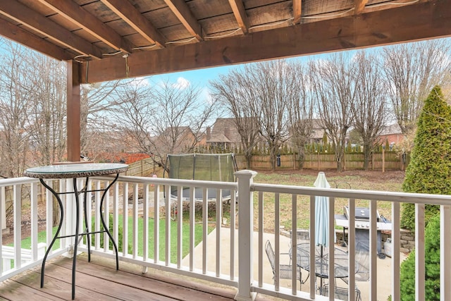 wooden terrace featuring a trampoline and a lawn