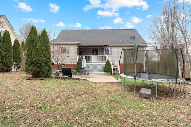 back of house featuring a trampoline, a lawn, and a patio