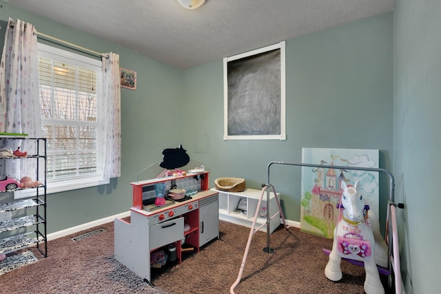 game room with a textured ceiling and dark colored carpet