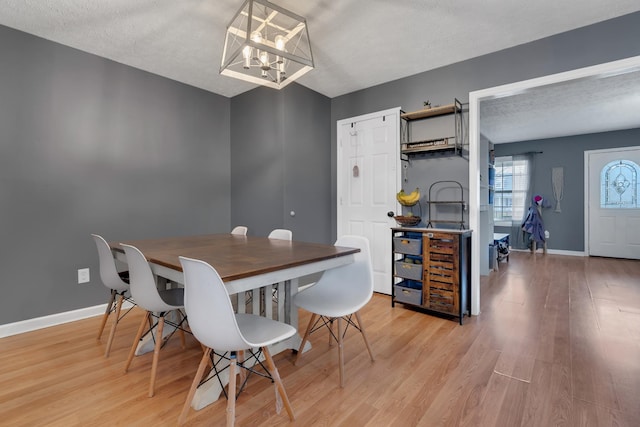 dining room with a notable chandelier, light hardwood / wood-style flooring, and a textured ceiling