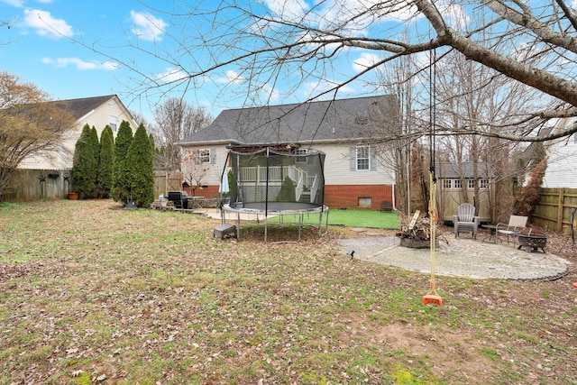 rear view of house featuring an outdoor fire pit, a yard, a patio area, and a trampoline