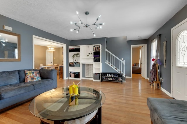 living room with a notable chandelier, light hardwood / wood-style flooring, and a textured ceiling