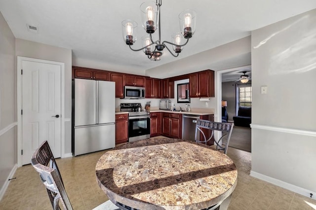 kitchen with pendant lighting, sink, ceiling fan with notable chandelier, and appliances with stainless steel finishes