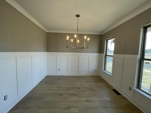 unfurnished dining area with crown molding, hardwood / wood-style floors, and a notable chandelier