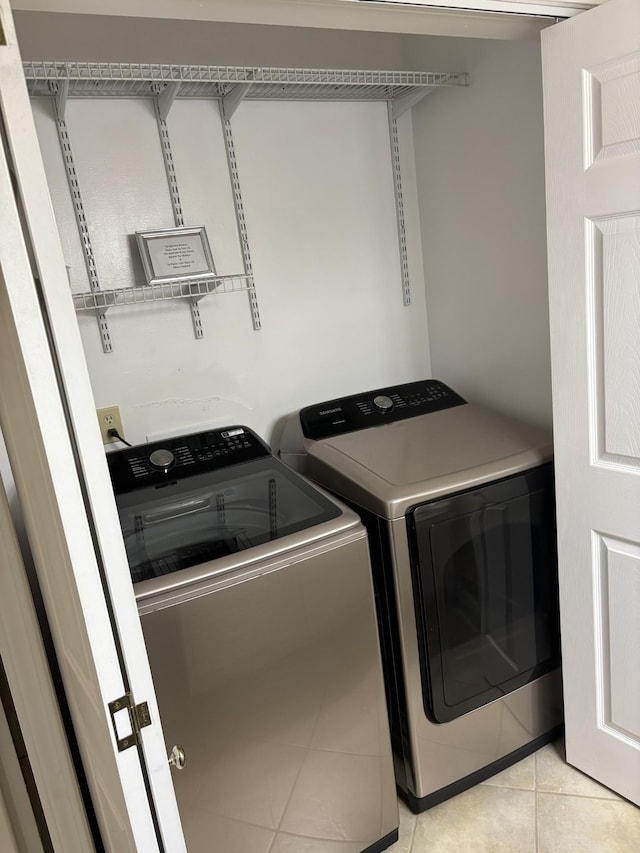 clothes washing area featuring washing machine and dryer and light tile patterned floors