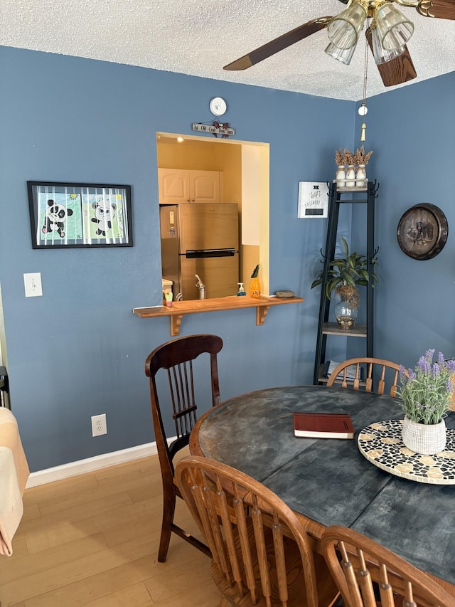 dining room with hardwood / wood-style floors, a textured ceiling, and ceiling fan