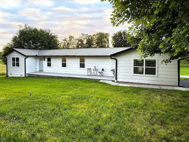 back house at dusk featuring a yard and a patio