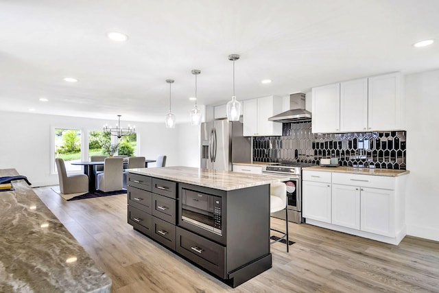 kitchen with white cabinetry, appliances with stainless steel finishes, and wall chimney range hood